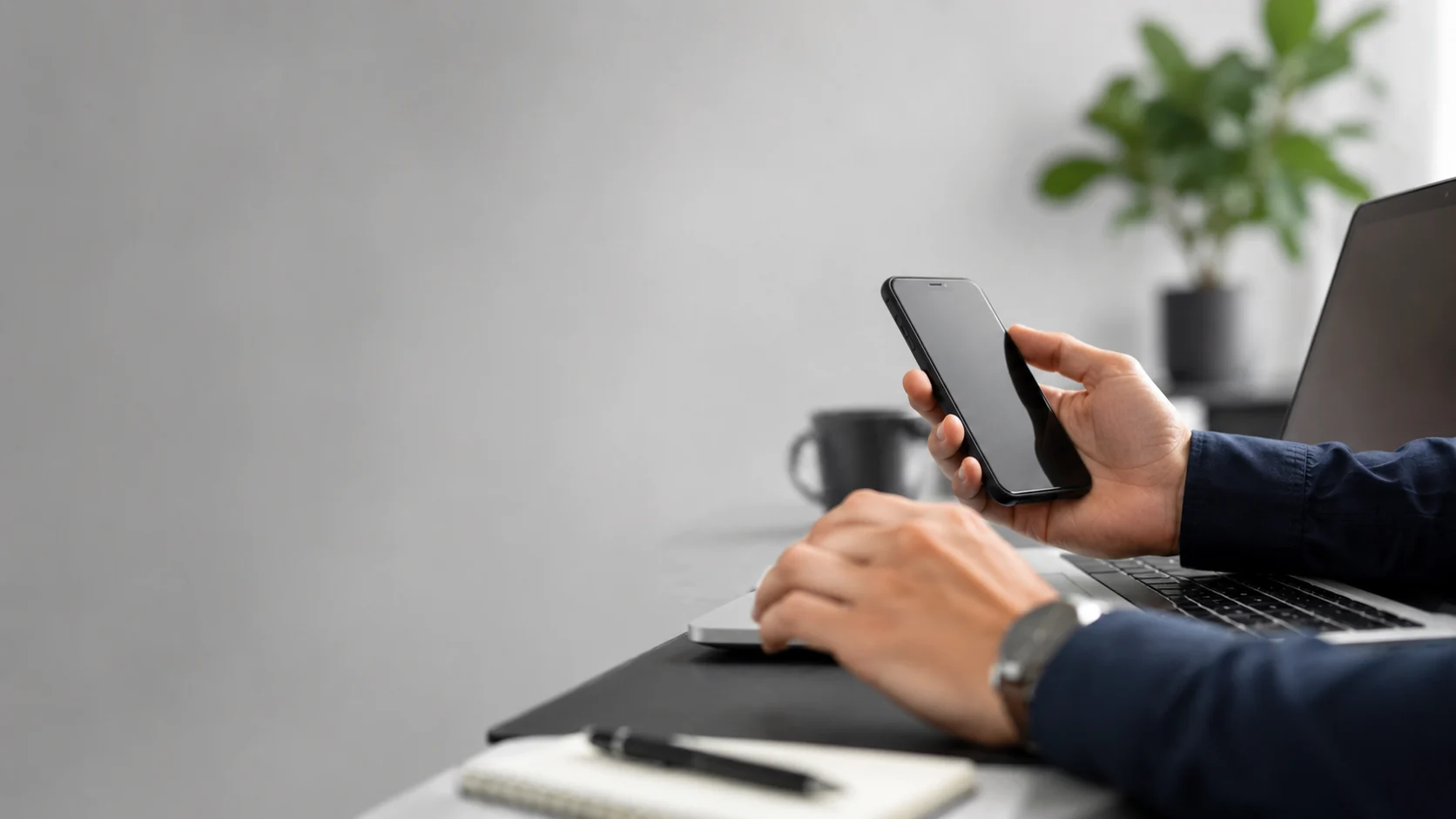 Manos escribiendo un mensaje en el teléfono junto a una laptop, la vía más rápida para contactar a la agencia de marketing médico